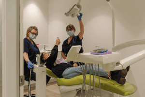 A woman gives the ok symbol regarding the benefits of regular dental care maintenance